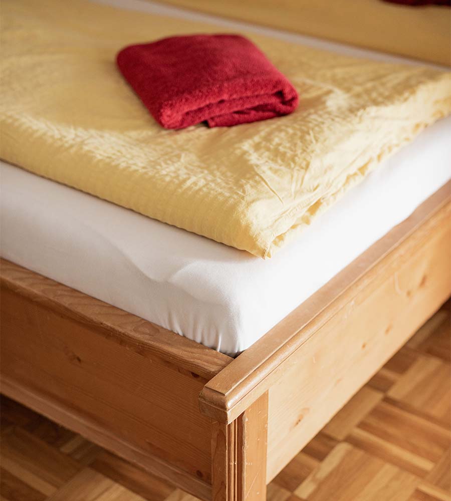 Bezogenes Bett und rotes Handtuch