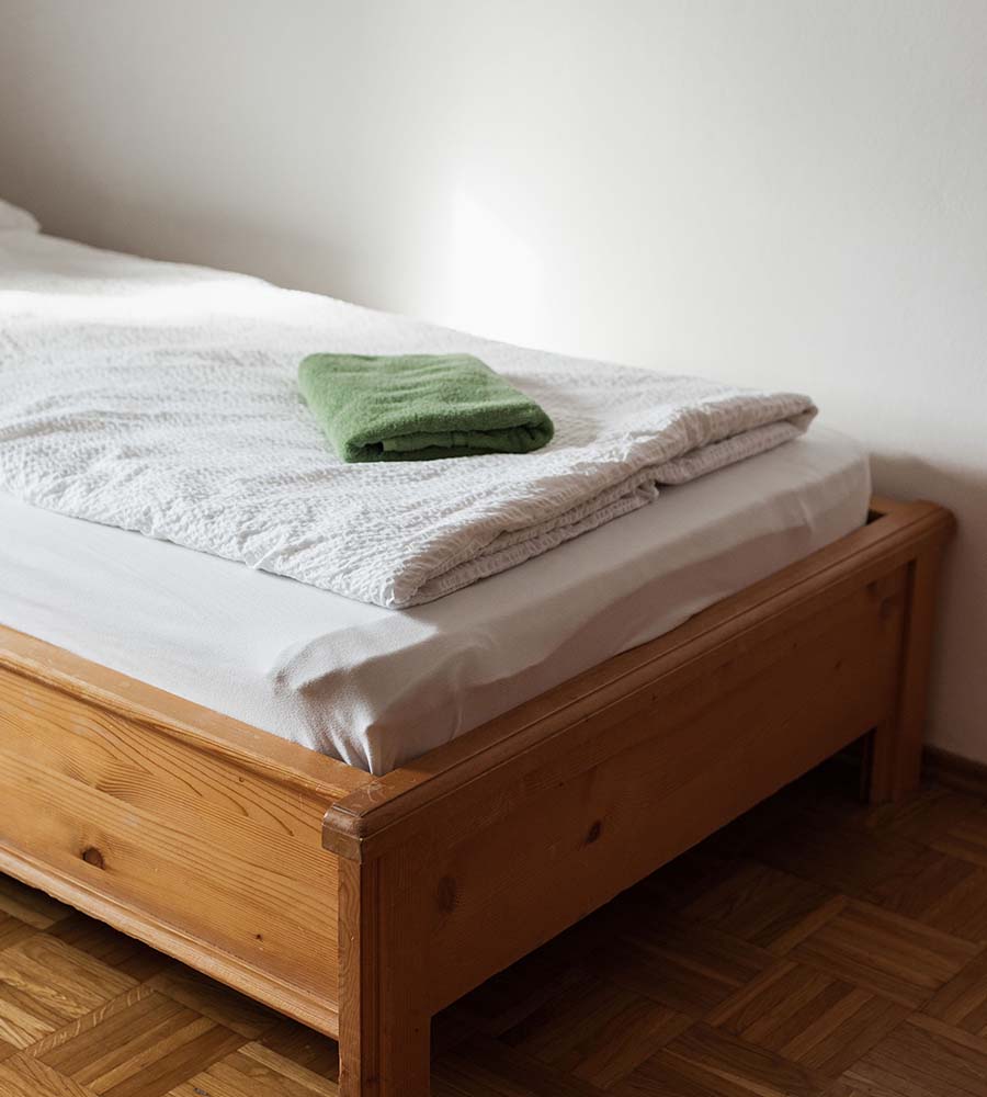 Grünes Handtuch auf bezogenem Bett